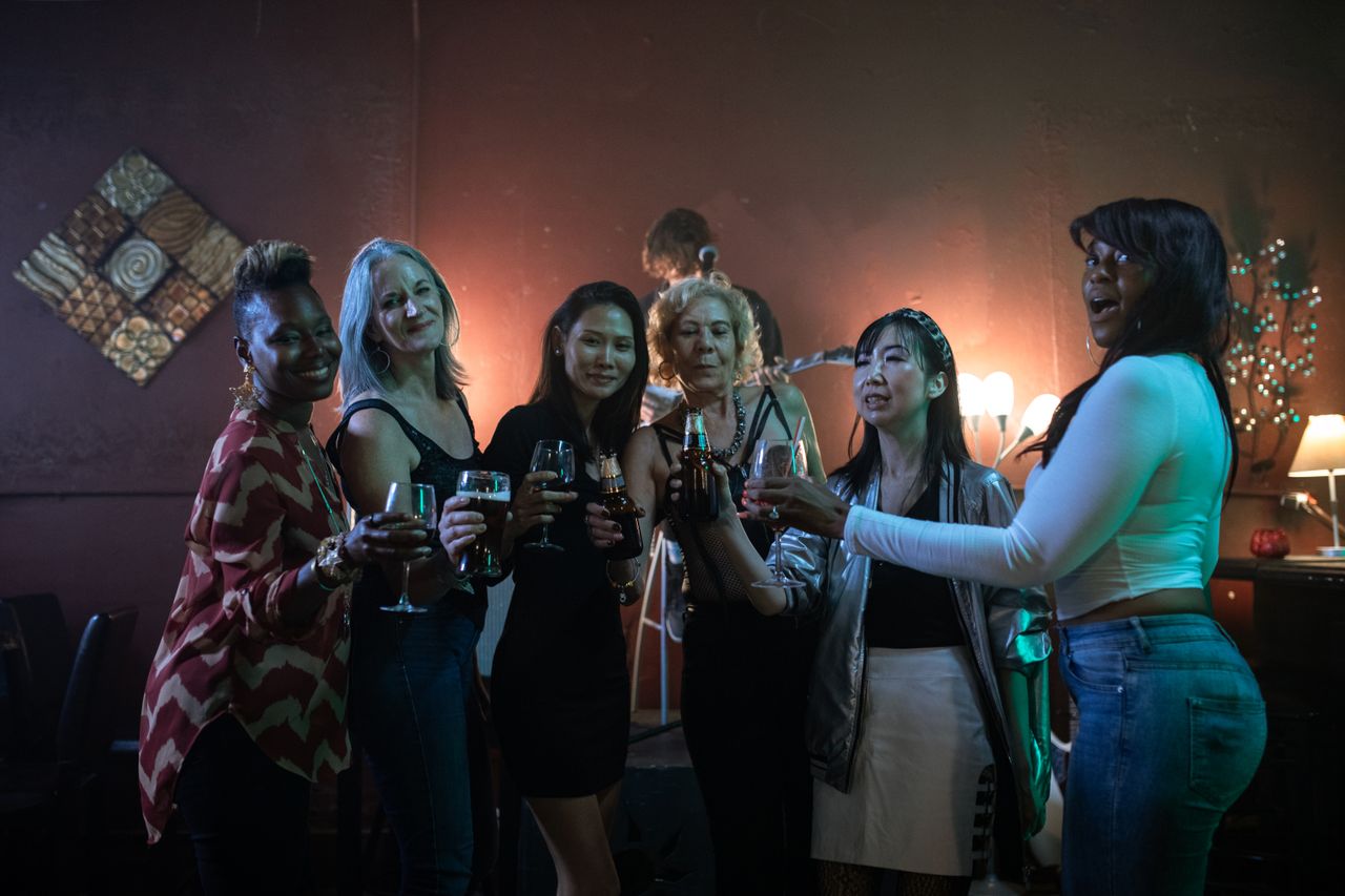 A group of women celebrating a fun night out at a bar, holding drinks and smiling.
