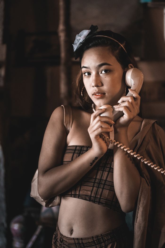 Fashionable young woman with vintage phone in a stylish indoor setting.